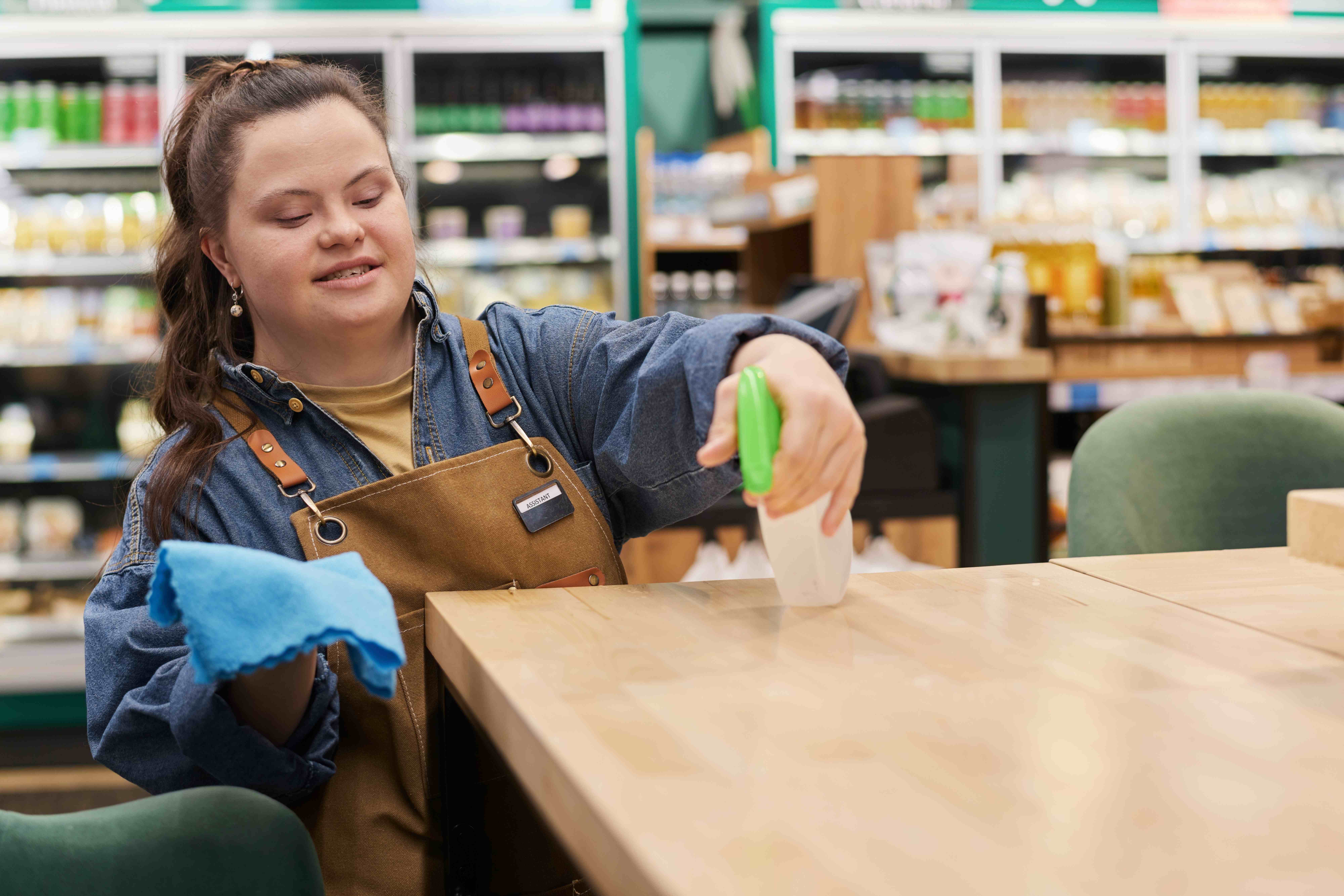 Young woman with Down syndrome working confidently in grocery store, demonstrating successful employment inclusion